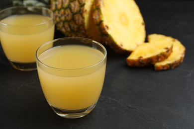 Photo of Delicious fresh pineapple juice on black table