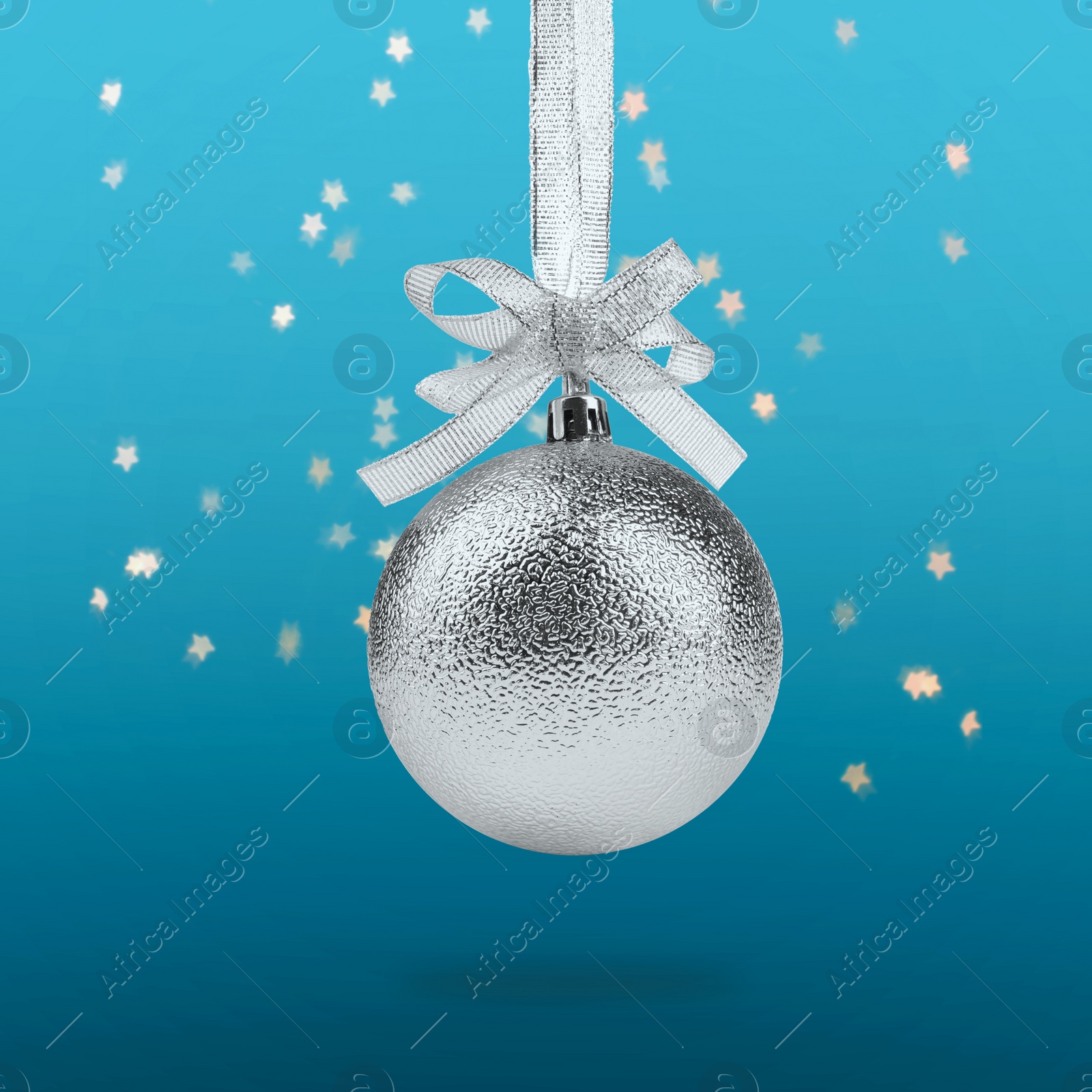 Image of Beautiful silver Christmas ball with bow hanging on light blue background