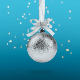 Image of Beautiful silver Christmas ball with bow hanging on light blue background