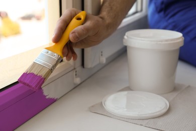 Image of Man painting window frame at home, closeup