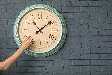 Woman pointing on clock against brick wall. Time concept