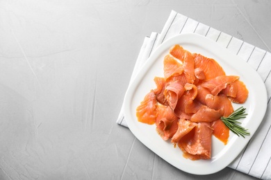 Photo of Plate with fresh sliced salmon fillet and rosemary on gray background, top view