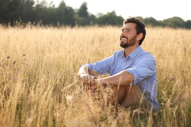 Photo of Happy man enjoying feeling of freedom on reed grass meadow