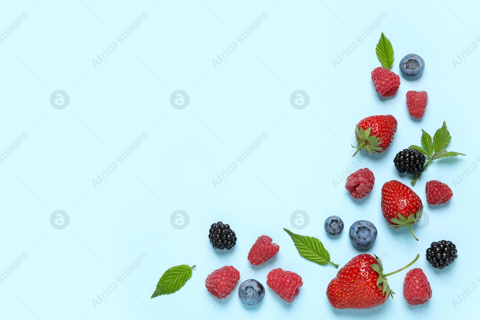 Photo of Different fresh berries on light blue background, flat lay. Space for text