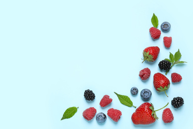 Photo of Different fresh berries on light blue background, flat lay. Space for text