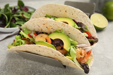 Photo of Delicious tacos with shrimps and avocado on light grey table, closeup