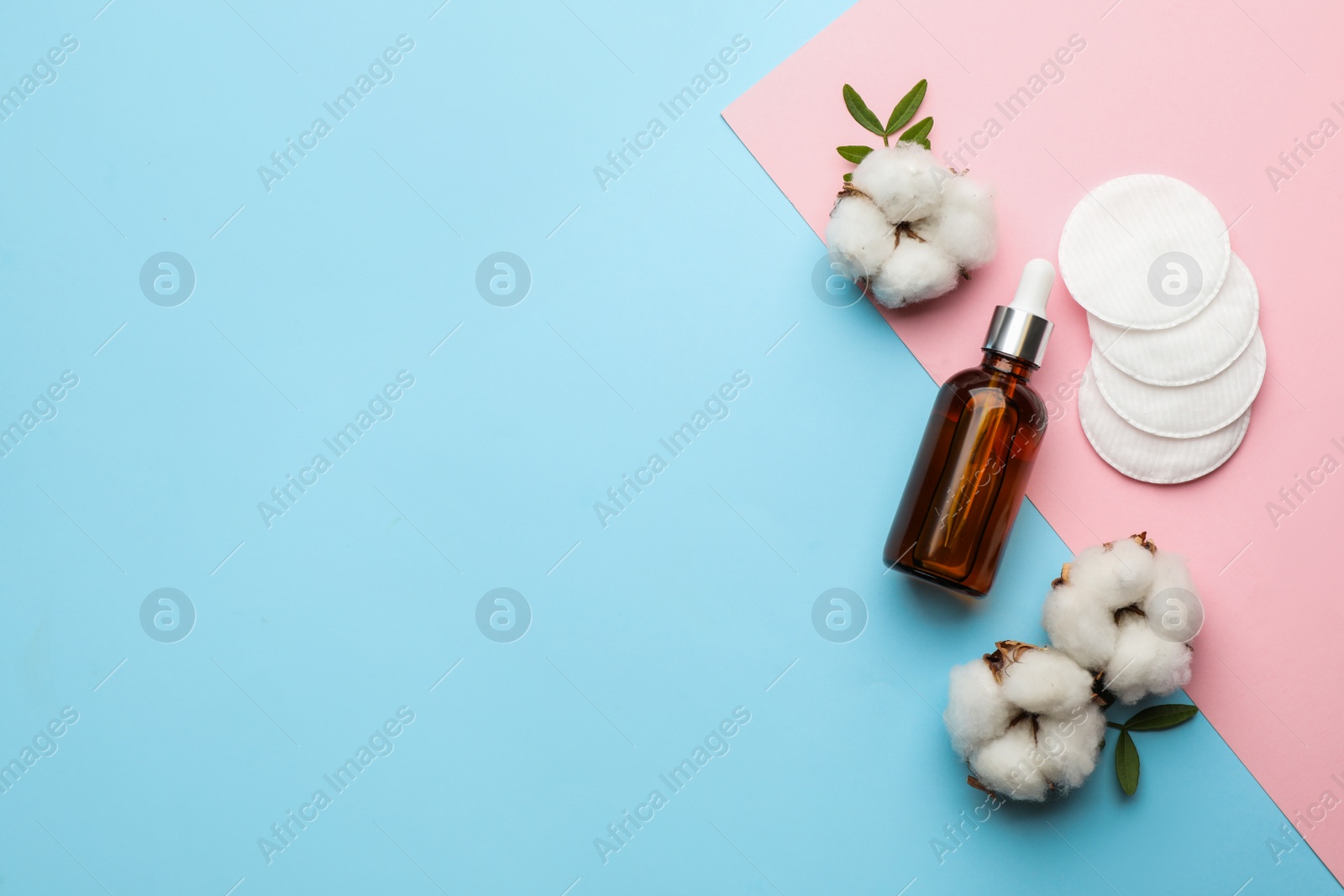 Photo of Cotton pads, flowers and makeup removal product on color background, flat lay. Space for text