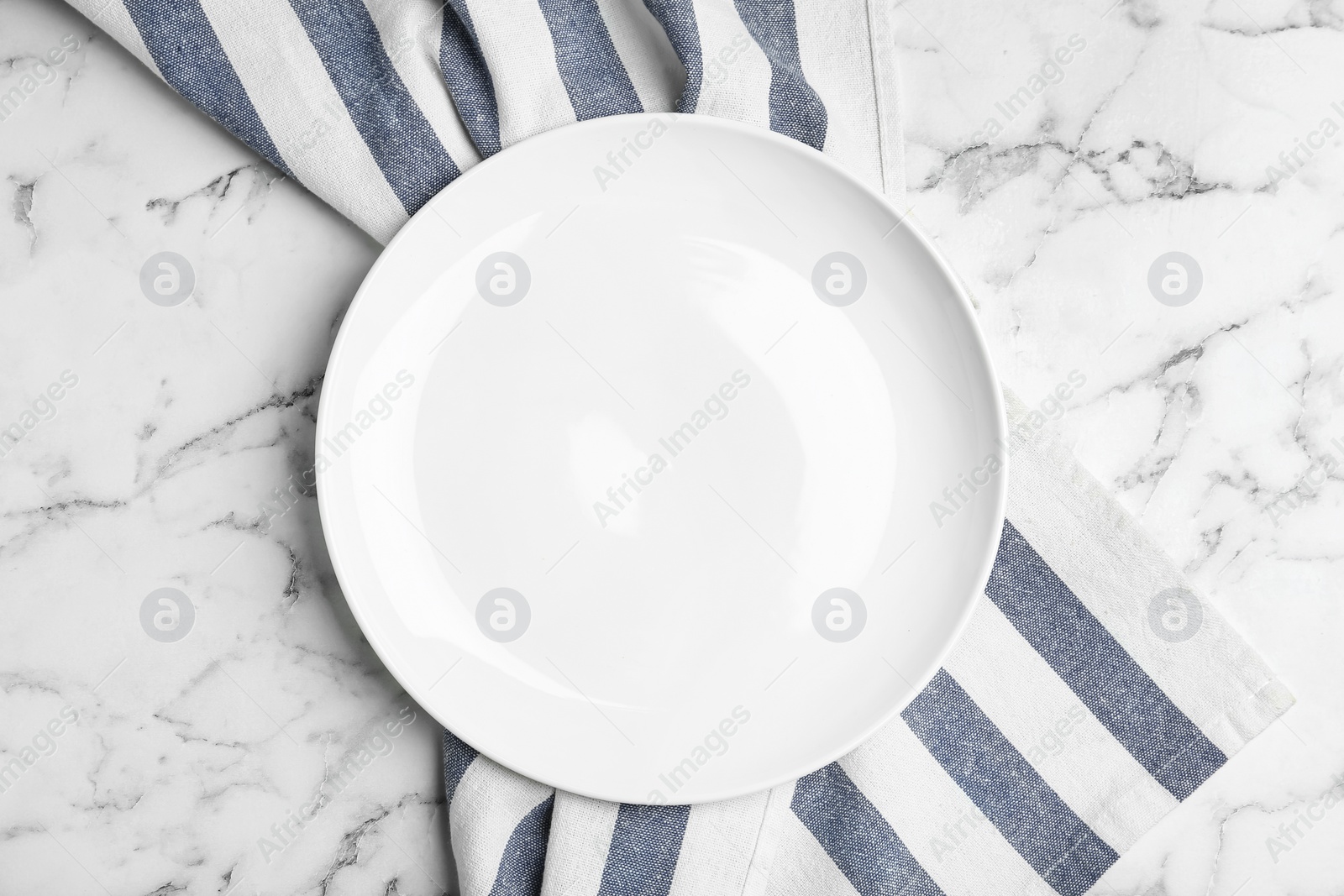 Photo of Empty plate and fabric on white marble table, flat lay