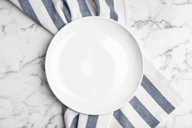 Photo of Empty plate and fabric on white marble table, flat lay