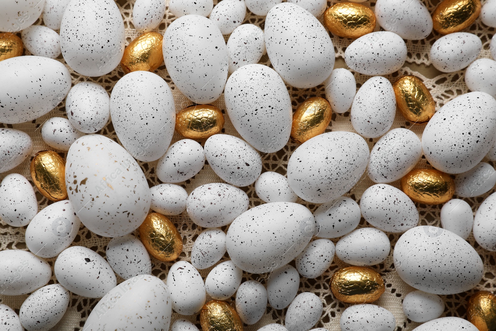 Festively decorated Easter eggs on knitted lace fabric, flat lay Photo of Festively decorated Easter eggs on knitted lace fabric, flat lay
