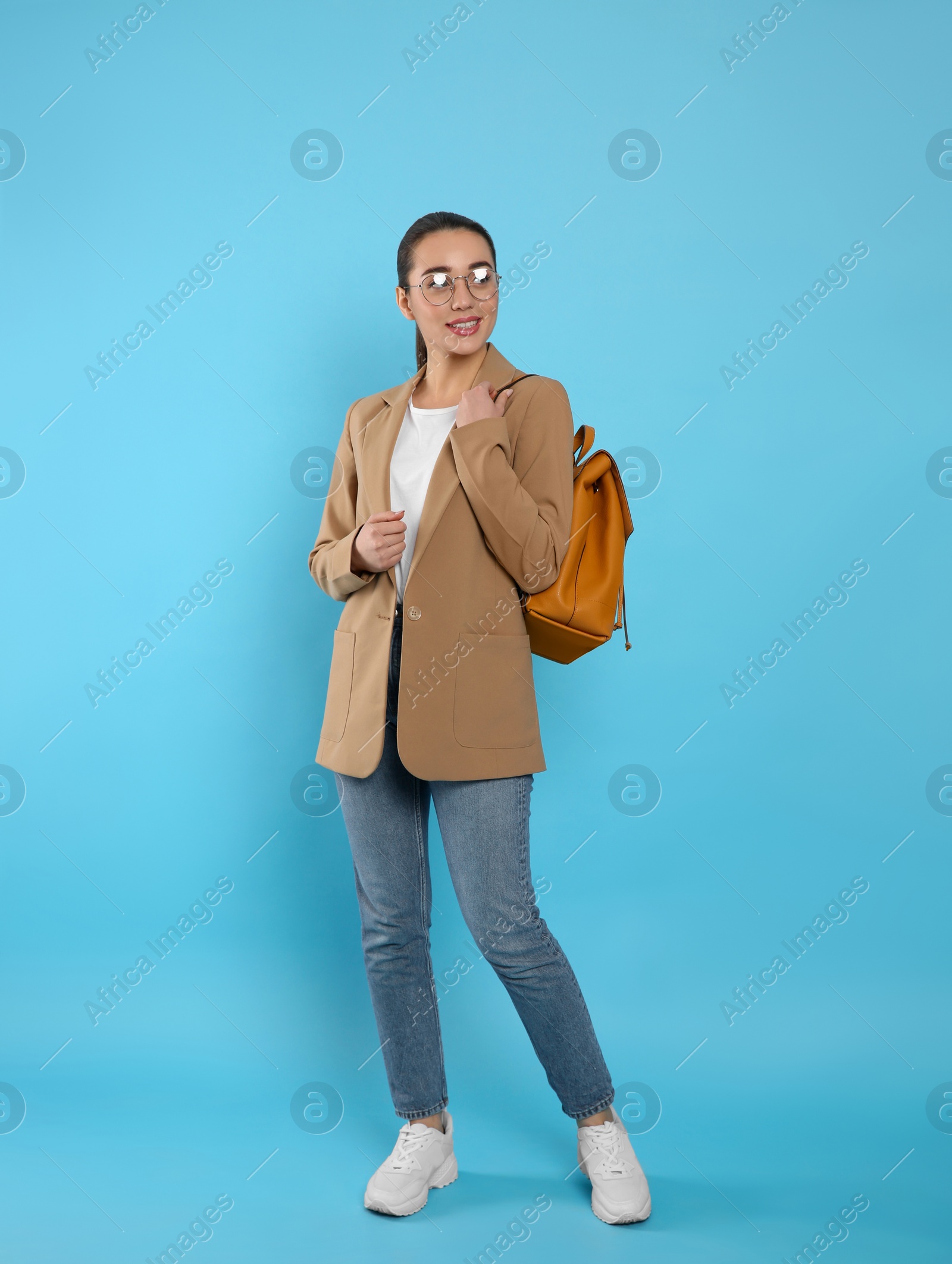 Photo of Beautiful young woman with stylish leather backpack on turquoise background