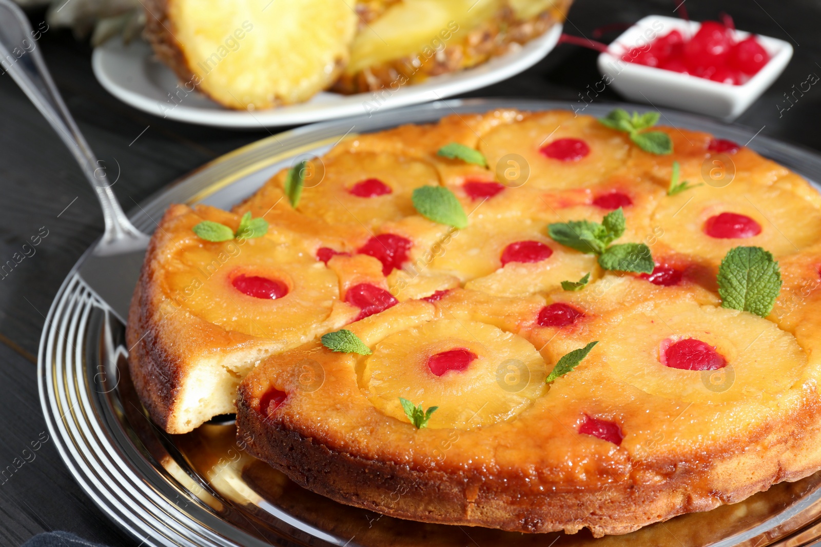 Photo of Taking piece of delicious cut pineapple pie with cherry and mint at table, closeup