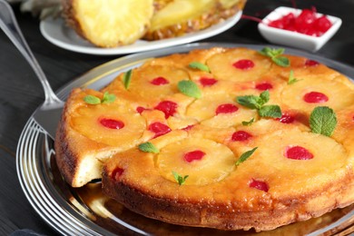 Taking piece of delicious cut pineapple pie with cherry and mint at table, closeup