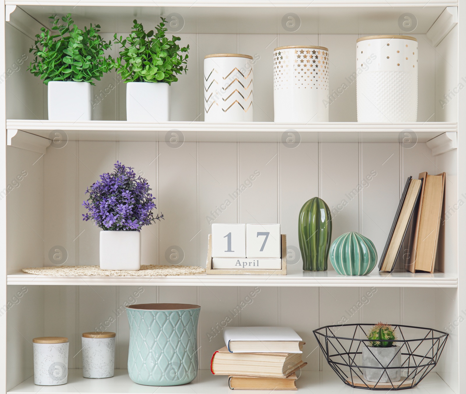 Photo of White shelving unit with plants and different decorative stuff