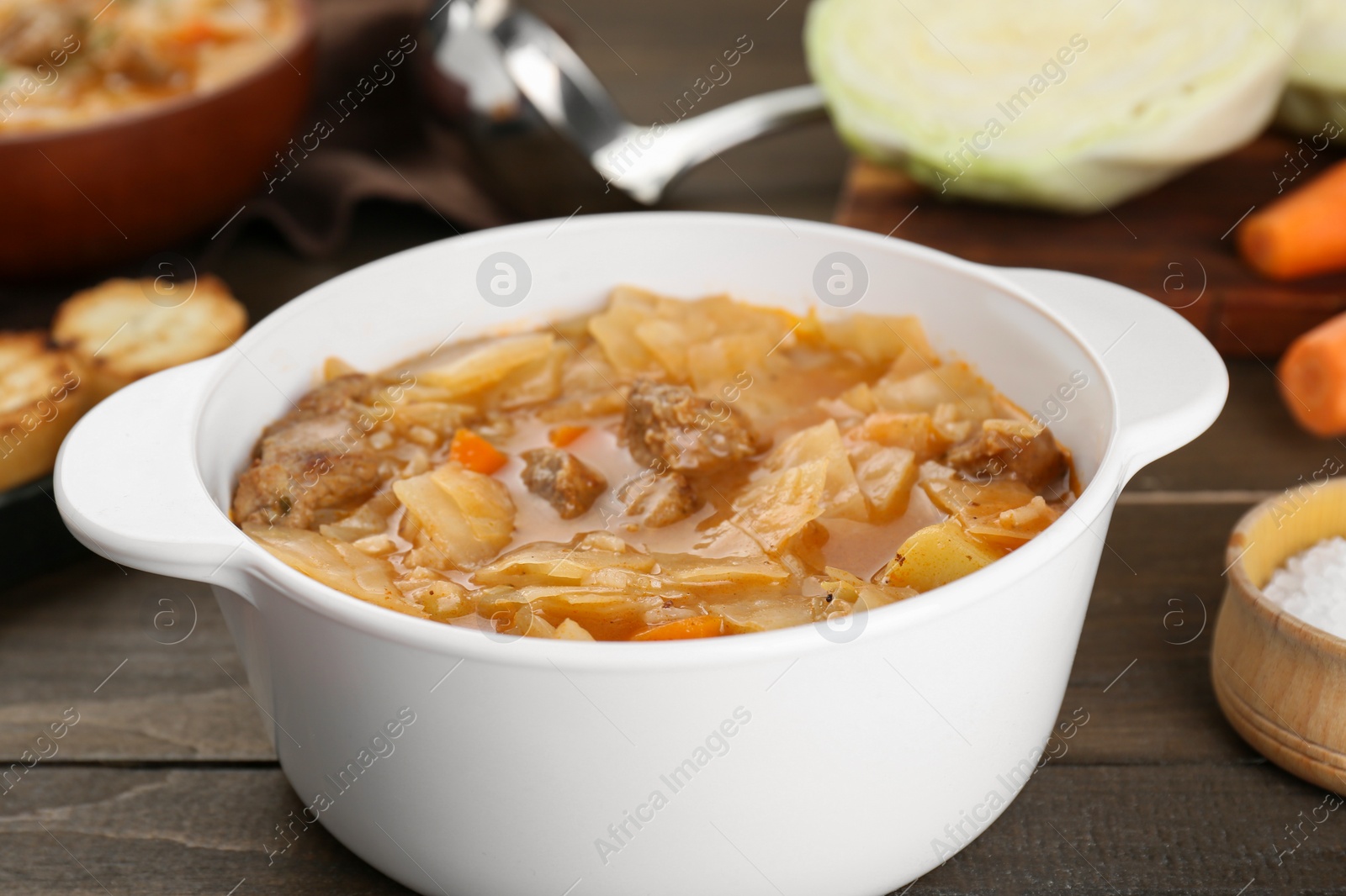 Photo of Tasty cabbage soup with meat and carrot on wooden table, closeup