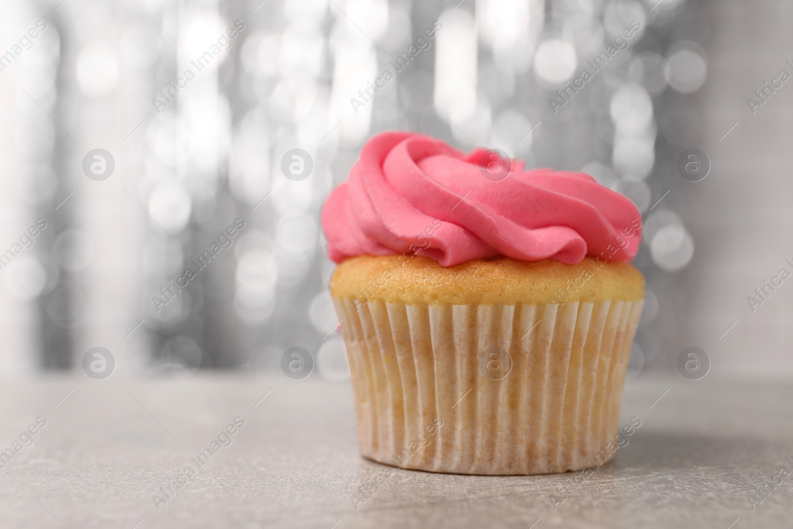 Photo of Delicious cupcake with bright cream on grey table, closeup. Space for text