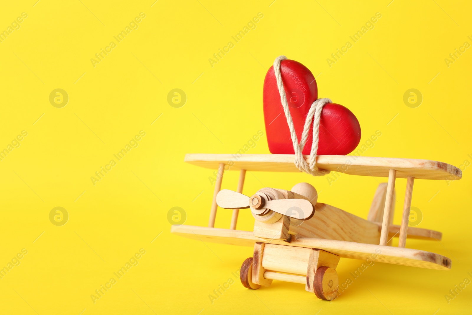 Photo of Small wooden airplane with heart on color background, space for text