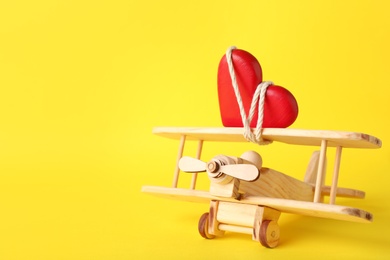 Photo of Small wooden airplane with heart on color background, space for text