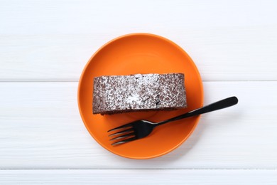 Piece of tasty chocolate sponge cake with powdered sugar on white wooden table, top view