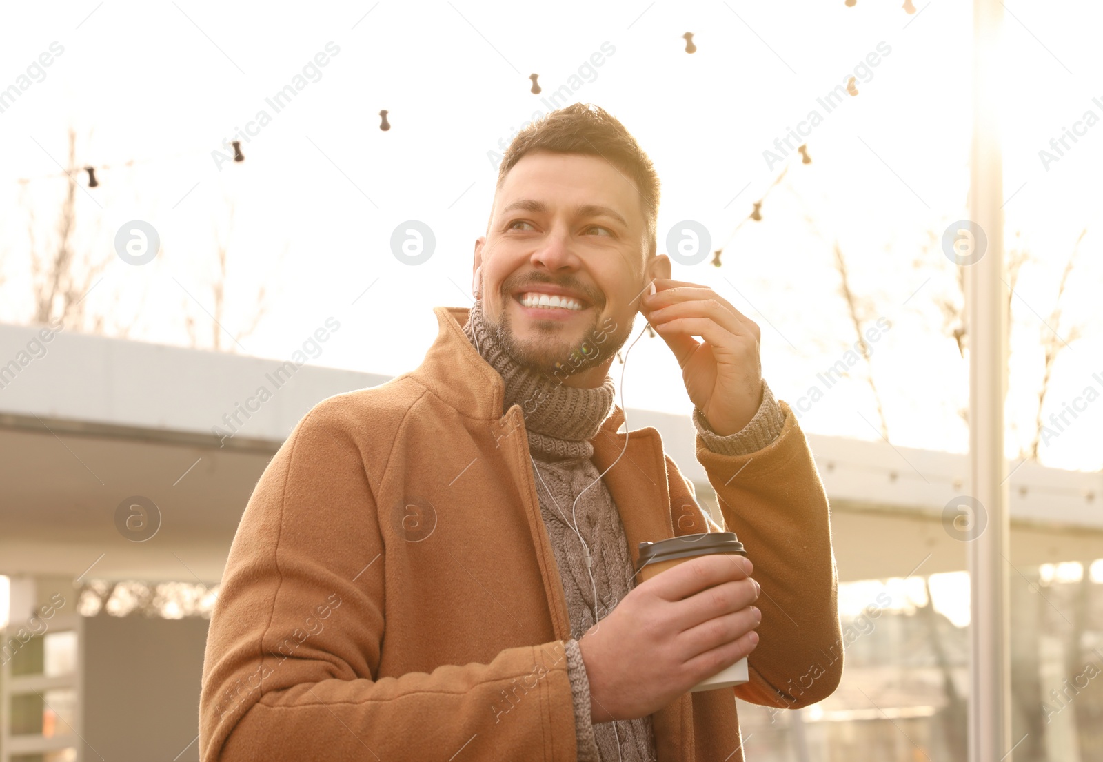 Photo of Man with cup of coffee on city street in morning