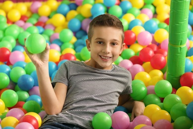 Cute little child playing in ball pit at indoor amusement park