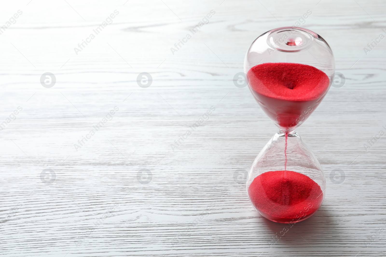 Photo of Hourglass with flowing red sand on wooden background. Time management