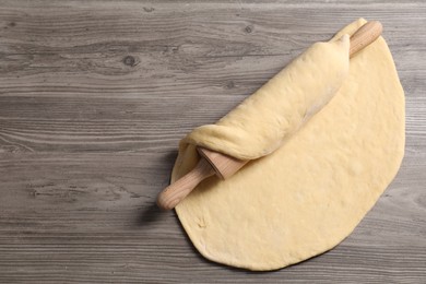 Raw dough and rolling pin on wooden table, top view. Space for text