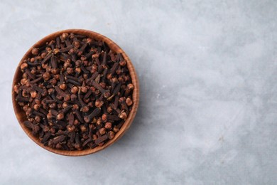 Photo of Aromatic cloves in bowl on gray table, top view. Space for text