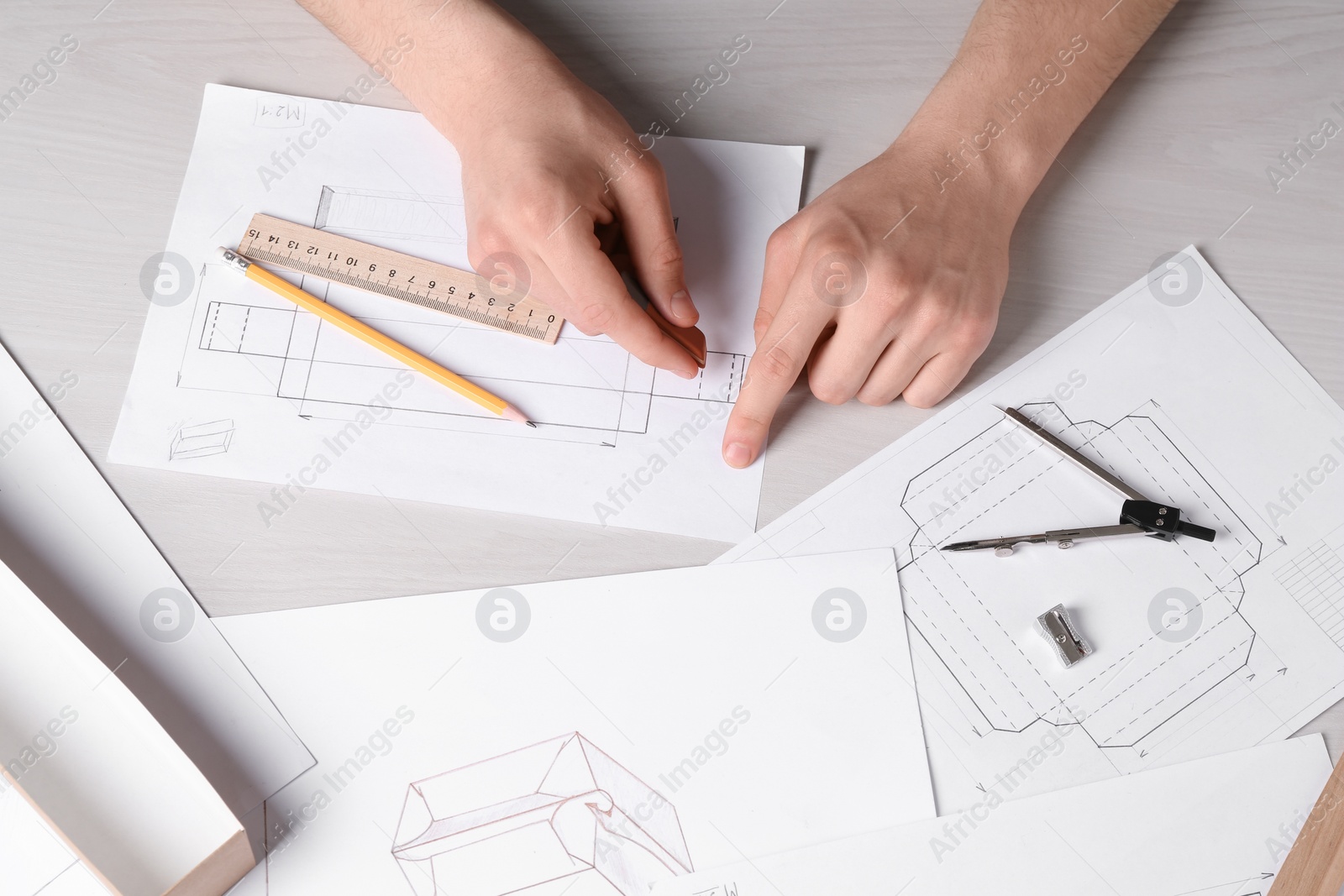 Photo of Man creating packaging design at light wooden table, top view