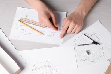 Man creating packaging design at light wooden table, top view