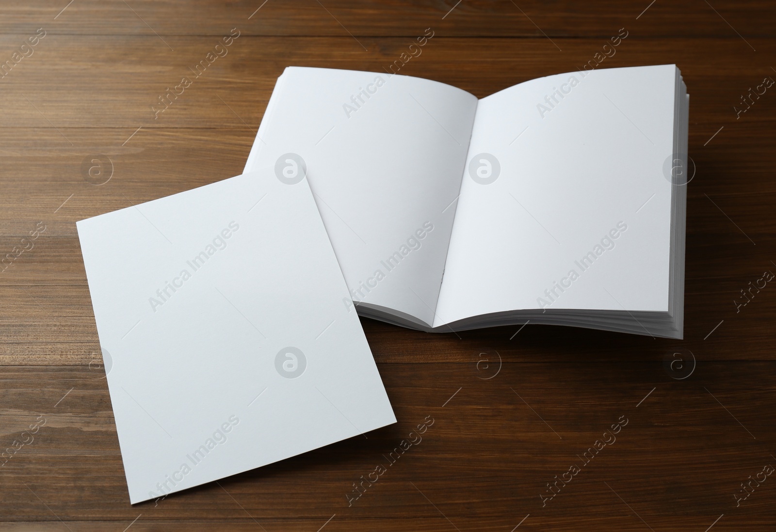 Photo of Sheet of paper and blank brochure on wooden table. Mockup for design