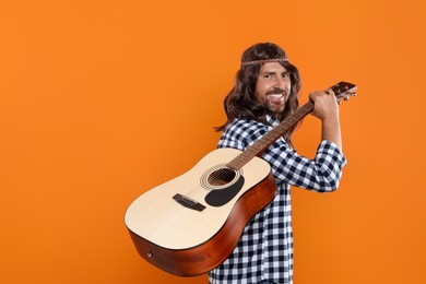 Photo of Hippie man with guitar on orange background, space for text