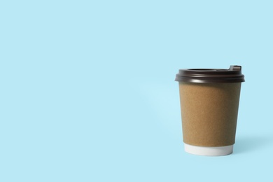 Photo of Takeaway paper coffee cup on light blue background. Space for text