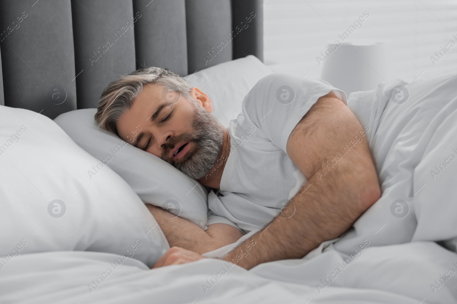 Photo of Man snoring while sleeping in bed at home