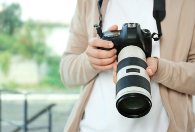Photo of Male photographer with professional camera on blurred background, closeup