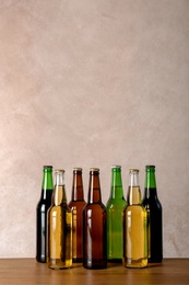 Photo of Bottles with different beer on table against color background