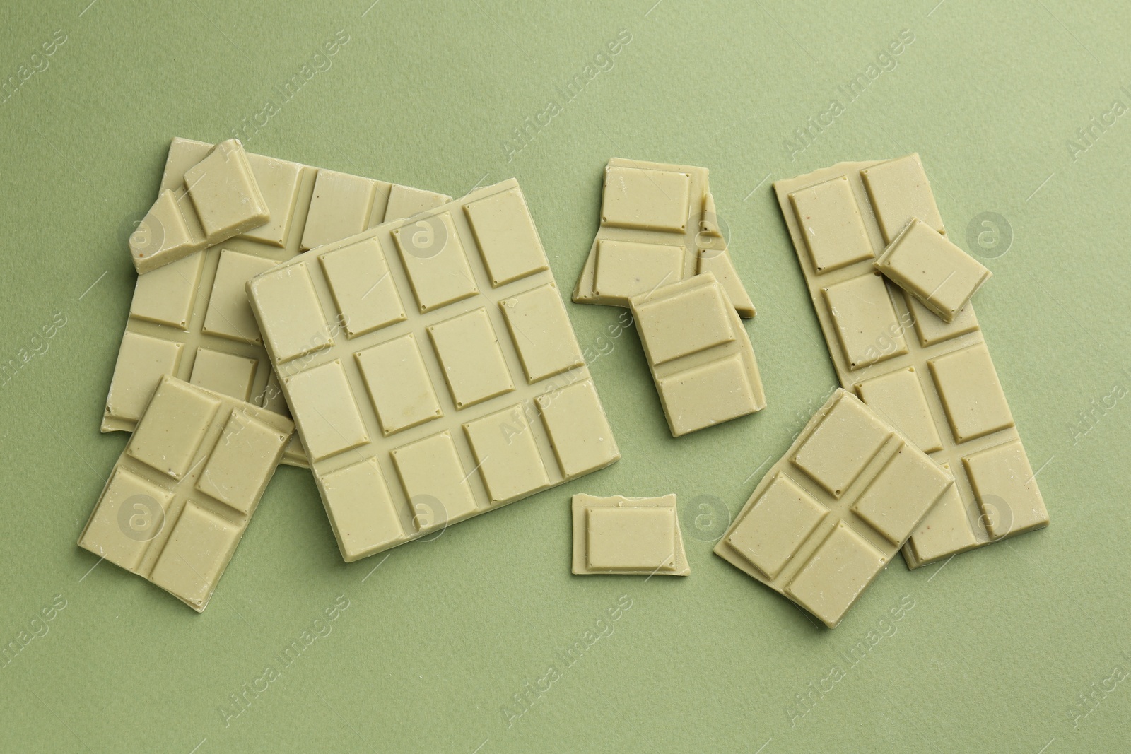 Photo of Pieces of tasty matcha chocolate bars on green background, top view