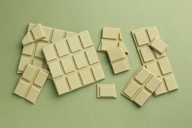 Pieces of tasty matcha chocolate bars on green background, top view
