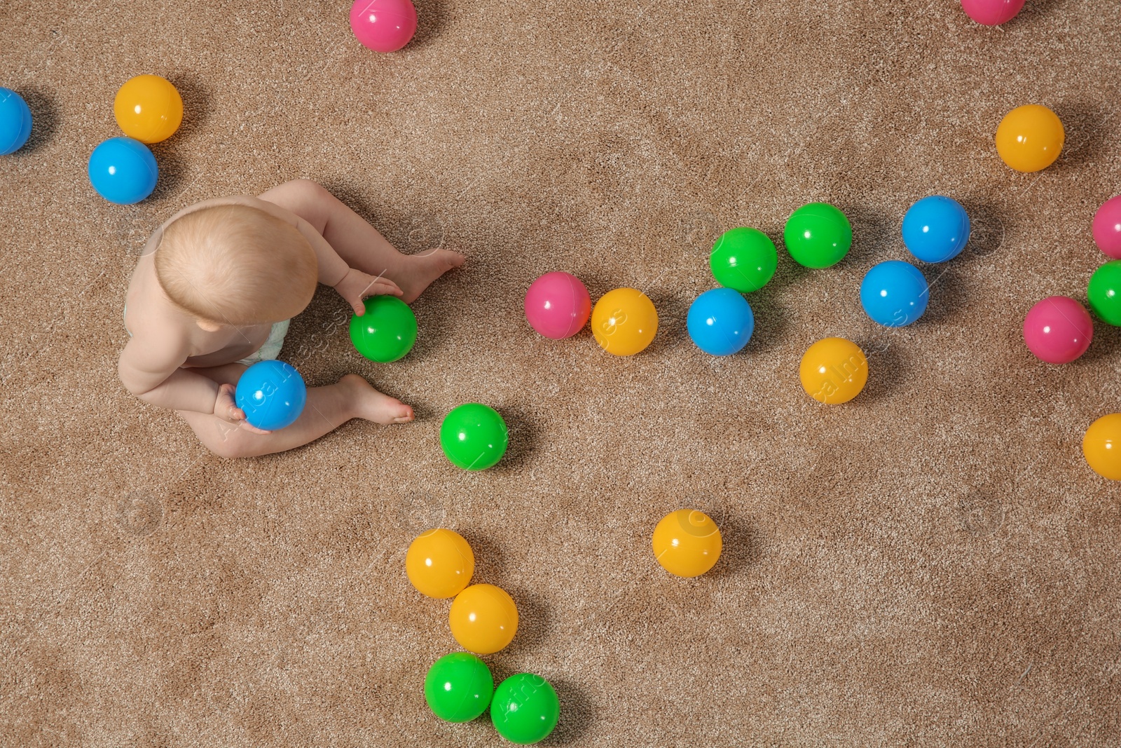 Photo of Cute little baby crawling on carpet with toys, top view