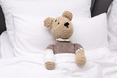 Photo of Toy cute bear with bandage under blanket in bed