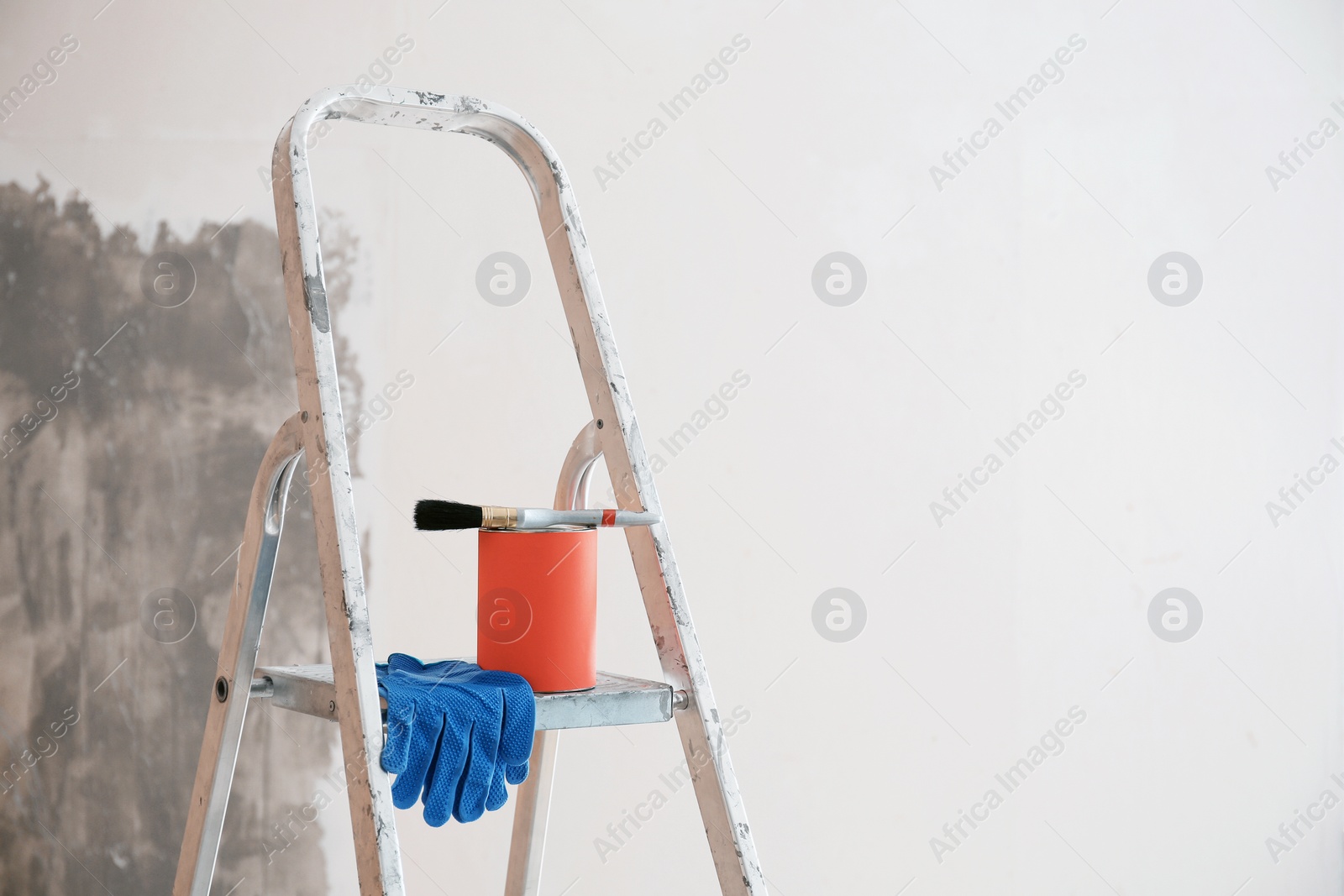 Photo of Can with paint and brush on step ladder in room