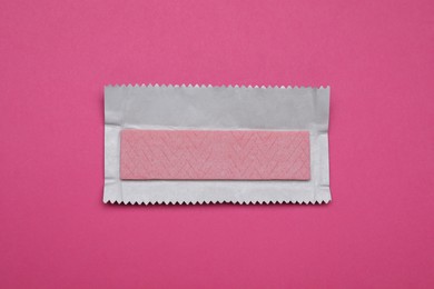 Photo of Unwrapped stick of tasty chewing gum on bright pink background, top view