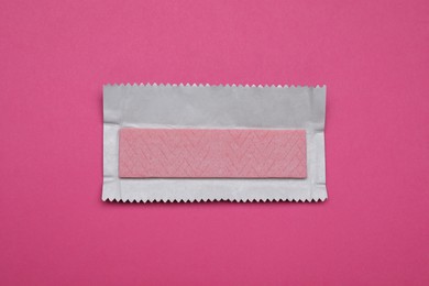 Unwrapped stick of tasty chewing gum on bright pink background, top view