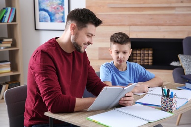 Photo of Dad helping his son with homework in room