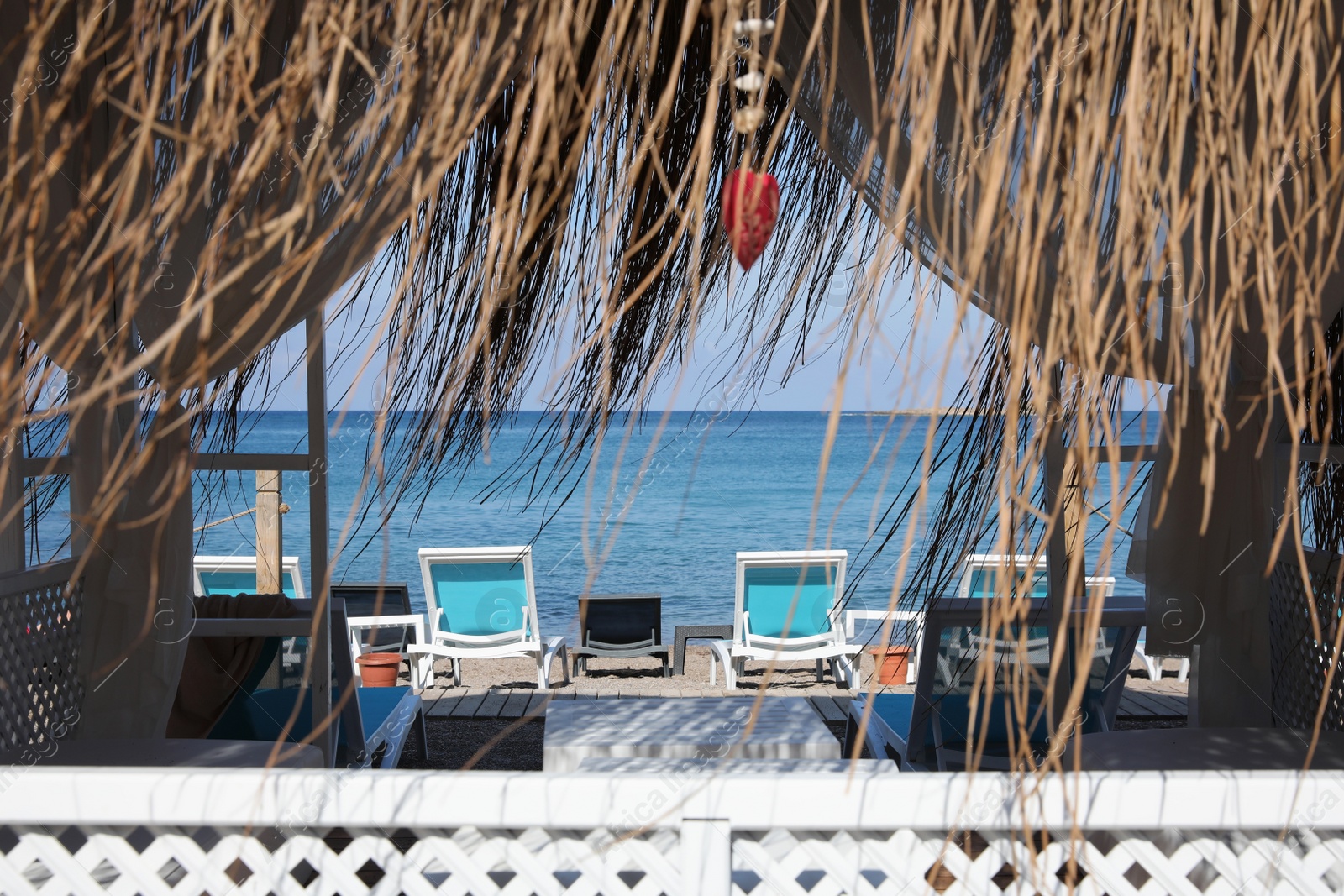 Photo of Comfortable hut and loungers on sea beach at resort