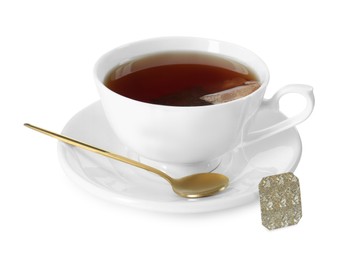 Photo of Brewing aromatic tea. Cup with teabag and golden spoon isolated on white