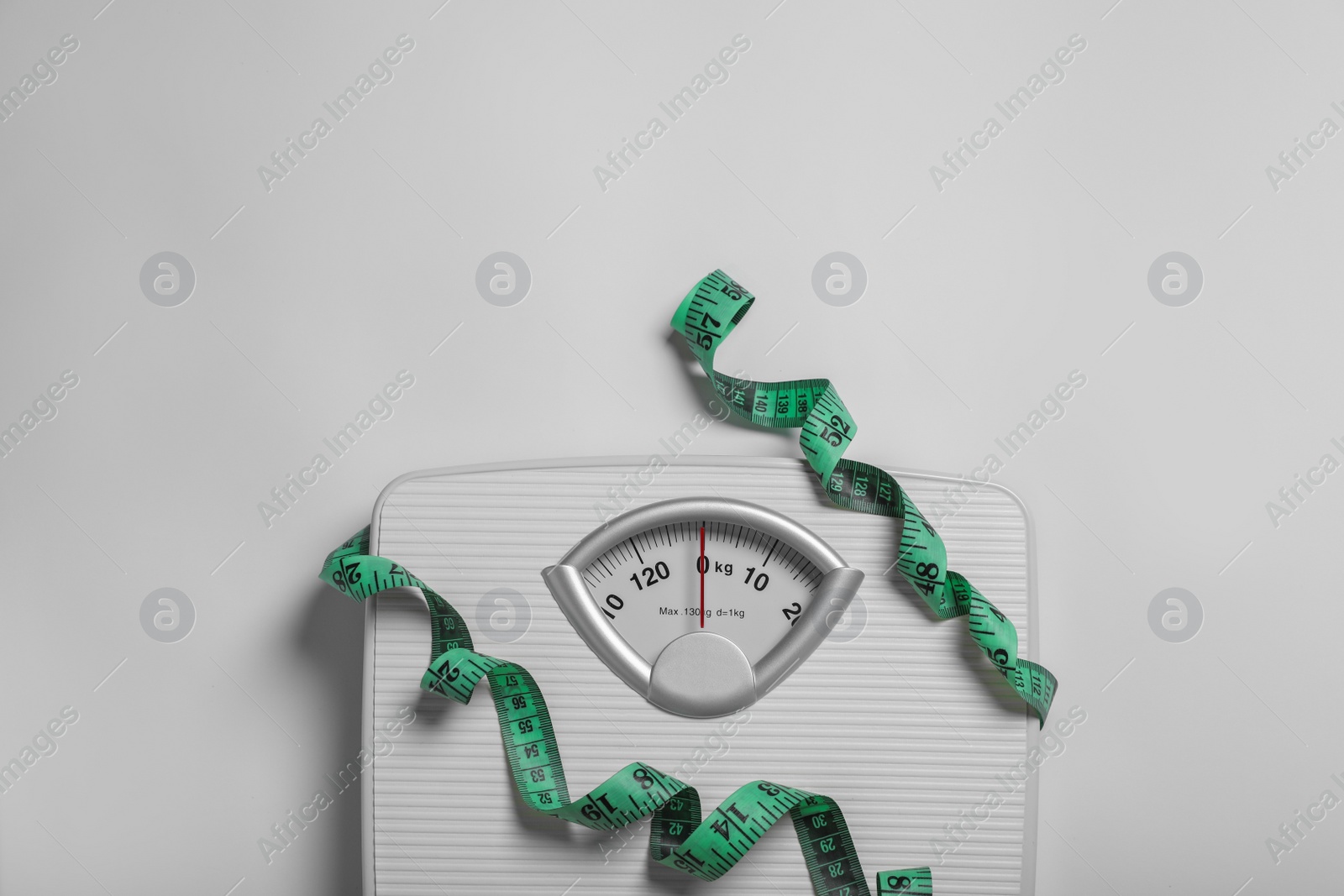 Photo of Weight loss concept. Scales and measuring tape on white background, top view. Space for text