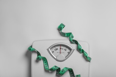 Weight loss concept. Scales and measuring tape on white background, top view. Space for text