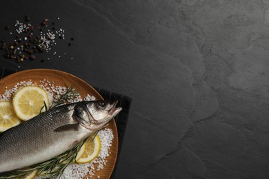 Photo of Sea bass fish and ingredients on black table, flat lay. Space for text