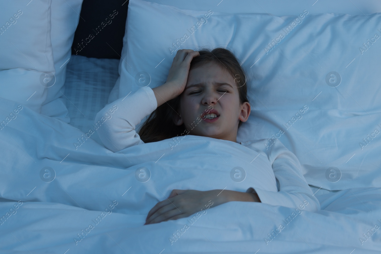 Photo of Little girl suffering from headache in bed at night